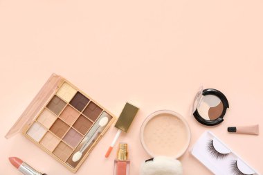 Göz makyajı için makyaj ürünleri, ruj ve bej arka planda pudra.