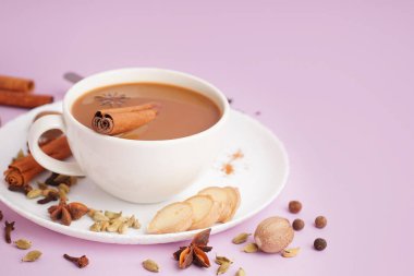 Mor arka planda farklı baharatlı bir fincan lezzetli masala çayı, yakın plan.