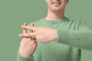 Yeşil arka planda parmakları olan hashtag işareti yapan adam, yakın plan