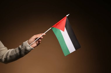 Karanlık arka planda Filistin bayrağı taşıyan bir kadın el.