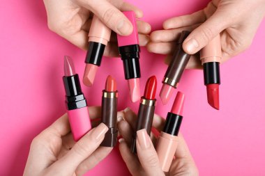 Pembe arka planda bir sürü ruju olan kadın elleri.