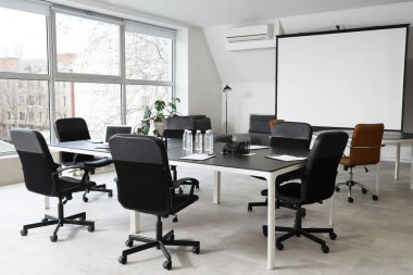 Masa, koltuk ve ekran kurulu konferans salonundaki iş toplantısı için hazırlandı.