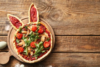 Ahşap zemin üzerinde lezzetli pizzalar olan bir tahta. Paskalya kutlaması