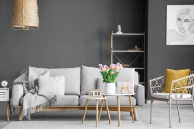 Uluslararası Kadınlar Günü için hediye kutusu ve laleleri olan oturma odasının masalarında.