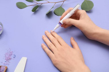 Tırnaklara, okaliptüs dalına ve leylak arkaplana deniz tuzu süren kadın elleri.