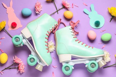 Paskalya yumurtaları, çiçekler ve mor arka planda kağıt tavşanlarla klasik patenler.