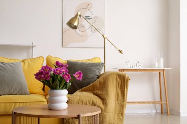 Oturma odasındaki masada pembe laleli vazo.