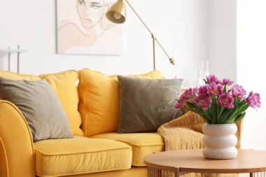 Oturma odasındaki masada pembe laleli vazo.