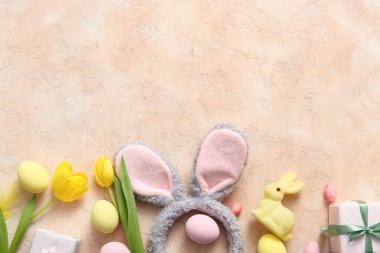 Paskalya yumurtalı tavşan kulakları, lale çiçekleri ve bej rengi grunge arka planda hediye kutuları.