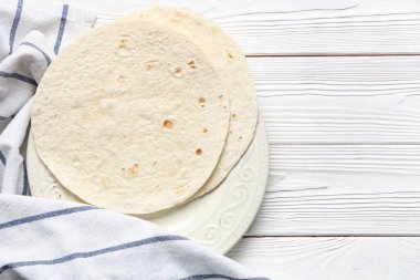 Hafif ahşap arka planda ince lavaş ve havluyla kompozisyon