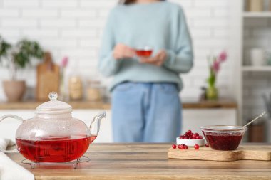 Mutfaktaki masada çaydanlık ve kızılcık reçeli var.