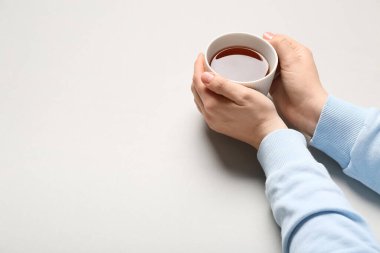 Kadın eli, arka planda bir fincan siyah çay tutuyor.