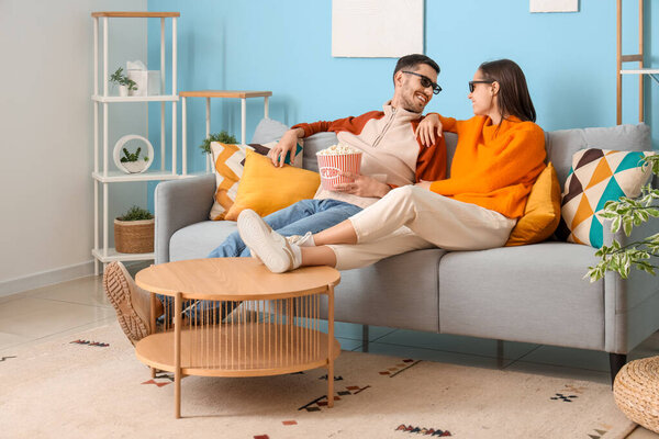 Красивая молодая счастливая пара с ведром попкорна вместе смотрят телевизор дома