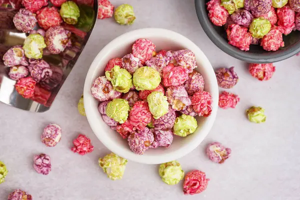 Beyaz arka planda tatlı renkli patlamış mısırlı kaseler ve metal kepçeler