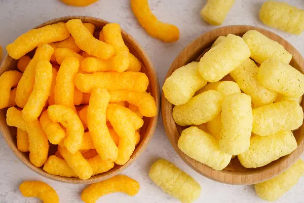 Farklı lezzetli, tuzlu mısır çubukları olan ahşap kaseler arka planda, yakın plan.