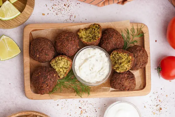 Nefis falafel köfteli ahşap tahta tahta tahta, limon, sos ve domates arkaplanda.