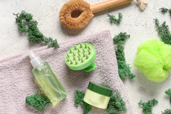 Beyaz grunge arka planda kozmetik ürünleri, havlu ve yosun içeren silikon kafa masajı fırçası