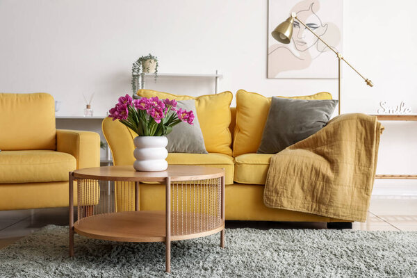 Vase with pink tulips on table in living room interior