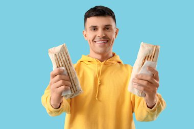 Mavi arka planda lezzetli donör kebabı olan mutlu genç adam.