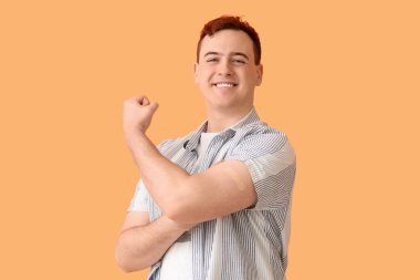 Bej arka planda uygulamalı tıbbi yama olan güç sembolü gösteren genç bir adam. Aşılama kavramı