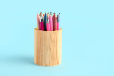 Mavi arka planda farklı kalemleri olan tahta tutucu