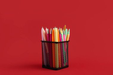 Kırmızı arkaplanda farklı kalemlerle tutucu