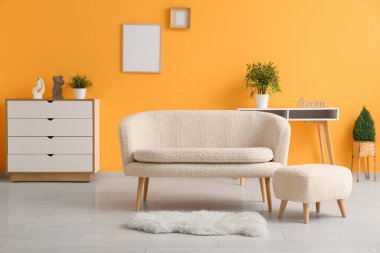 Beyaz kanepe, ayak sehpası ve halısı olan oturma odasının içinde.