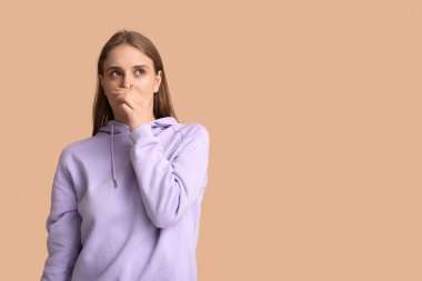 Bej arka planda iğrenç bir koku hisseden genç bir kadın.