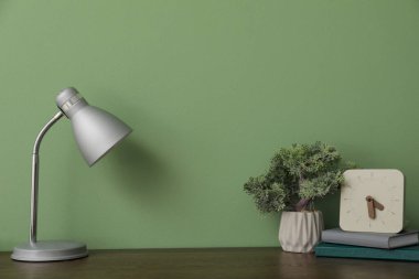 Bonsai ağacı, saati, defterleri ve yeşil arka planı olan ahşap masa.