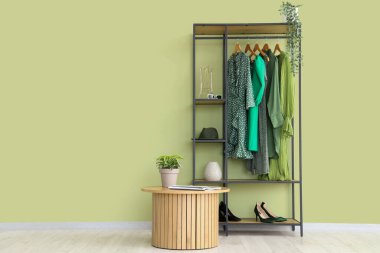 Renkli duvarın yanında şık kadın kıyafetleri, ayakkabıları ve aksesuarları rafa kaldırın.