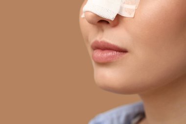 Kahverengi arka planda sargılı burunlu genç bayan, yakın plan. Estetik ameliyat konsepti