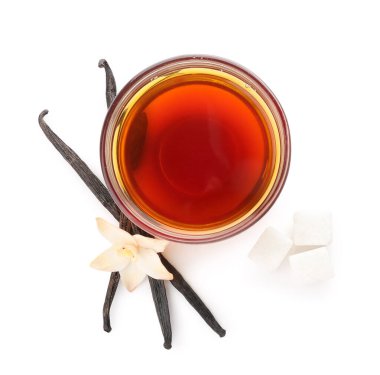 Beyaz arka planda bir kase vanilya özü, çubuk ve şeker.