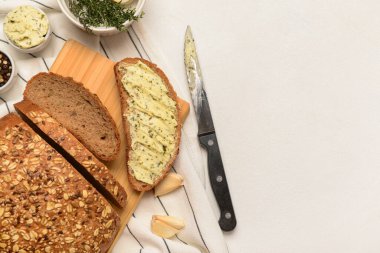 Tahta tahtada tereyağlı taze ekmek ve beyaz arka planda farklı baharatlar.