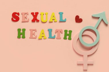 Pembe arka planda cinsiyetçi sağlık, erkek ve kadın sembolleri içeren renkli harfler.