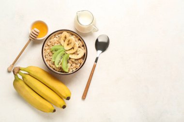 Lezzetli yulaf ezmeli kompozisyon, ballı kase, muz ve hafif arka planlı sütle sürahi.