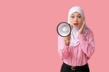 Genç Asyalı Müslüman kadını pembe arka planda megafonla şoke etti. Ulusal Duyulma Günü