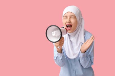 Genç Asyalı Müslüman kadın pembe arka planda megafona bağırıyor. Ulusal Duyulma Günü