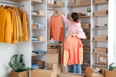 Soyunma odasında şık kıyafetler ayarlayan yakışıklı genç adam.