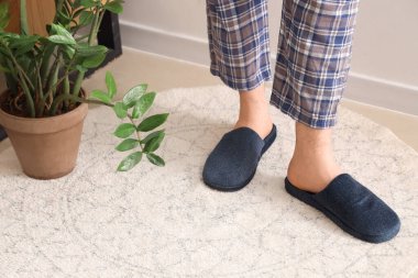 Evde mavi terlik giyen adamın bacakları. Yakın çekim.