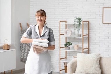 Oturma odasında temiz havlularla gülümseyen hizmetçi.