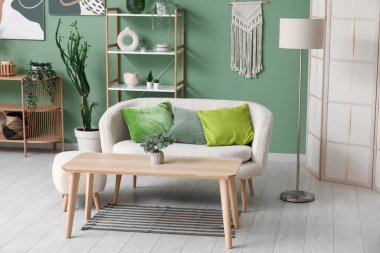 Rahat kanepesi, zeytin yastıkları ve ahşap masası olan modern oturma odasının içinde.