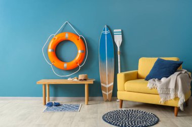 Oturma odasının içinde sörf tahtası, şamandıra ve koltuk var.