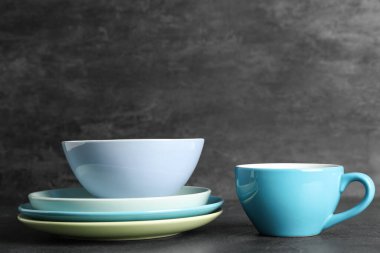 Masada siyah grunge arka planına karşı temiz sofra takımı ve fincan yığını