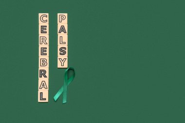 Yeşil arkaplanda CEREBRAL PALSY yazılı saten yeşil kurdele ve plastik harfler