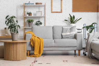 Gri kanepesi ve kahve masasında çiçekleri olan modern oturma odasının içinde.