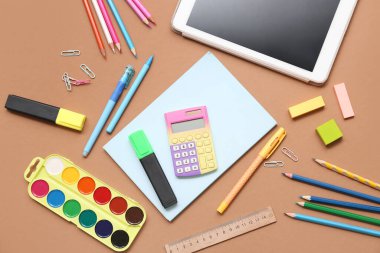 Tablet, hesap makinesi ve kahverengi arka planda işaretleyici. Üst görünüm