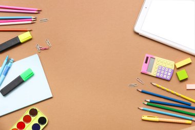 Tablet, hesap makinesi ve kahverengi arka planda işaretleyici. Üst görünüm