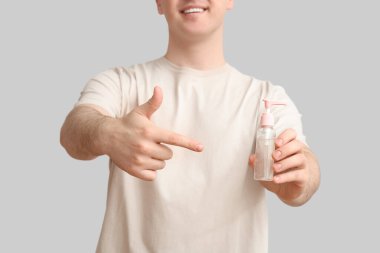 Hafif arka planda dezenfektanı olan genç adam, yakın plan.