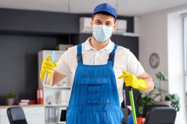 Ofisinde paspas ve deterjanı olan erkek temizlik işçisi.