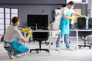 Temizlik servisinde çalışan erkek işçiler işyerlerini dezenfekte ediyorlar.